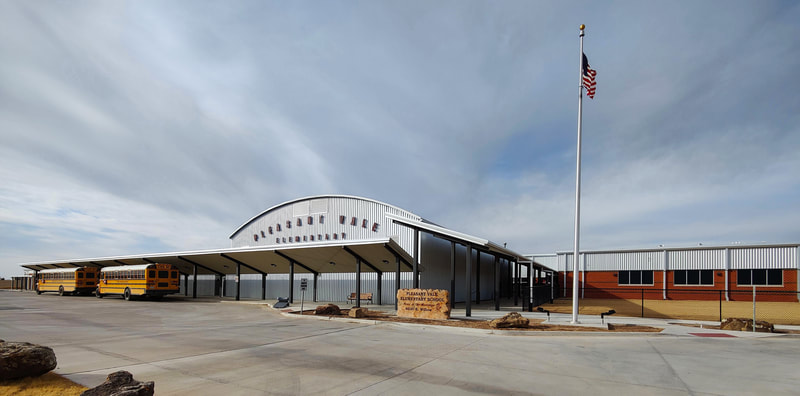 Pleasant Vale Elementary School exterior with metal and brick façade, covered walkways, and flag pole