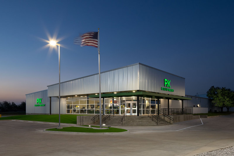 Exterior of P&K Equipment in Enid at twilight with metal and glass façade and entry